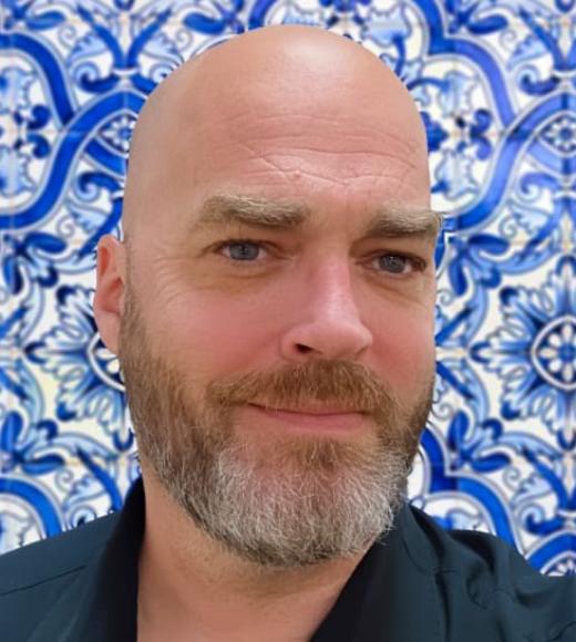 Image of a older gentleman, a handsome rover if you will. Bald with a beard and stunning blue eyes.